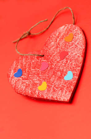multicolored paper hearths on a wooden red heart  on red paperの写真素材