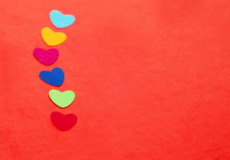 line of multicolored paper hearths on red paper