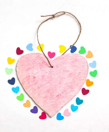 multicolored paper hearths with a wooden pink heart  on white paperの写真素材