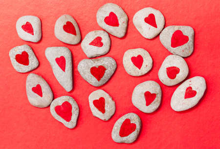 stones painted with red hearts on red paperの写真素材