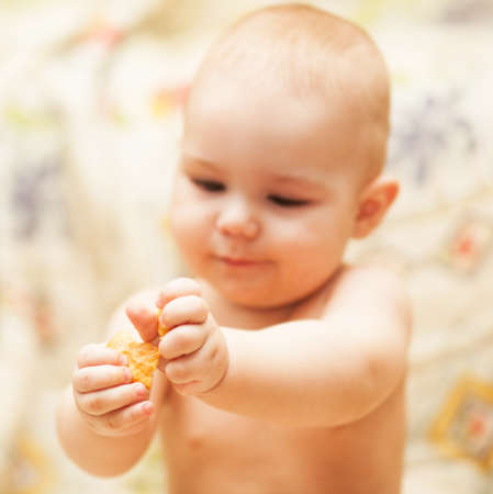 cute child learning to eat a biscuitの写真素材