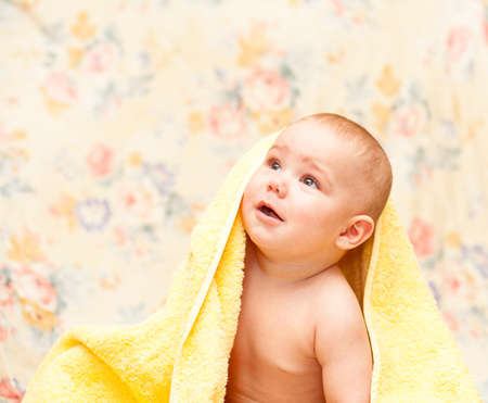 Baby crying in a yellow towel sitting  on the floorの写真素材