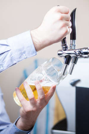 glass being filled with draft beer by barmanの写真素材