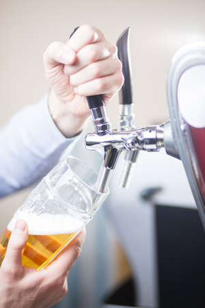 glass being filled with draft beer by barmanの写真素材