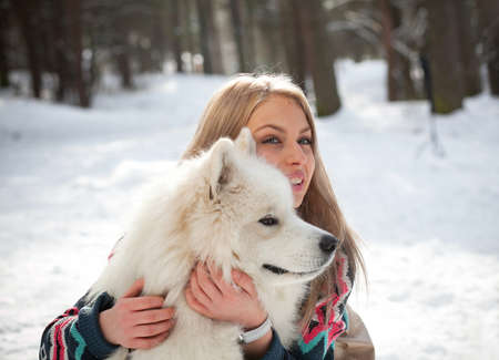 Girl in fur hat with samoyed dog in winter parkの写真素材