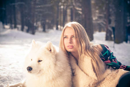 Girl in fur hat with samoyed dog in winter parkの写真素材