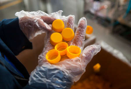 many orange plastic corks in the hand in the production .の写真素材