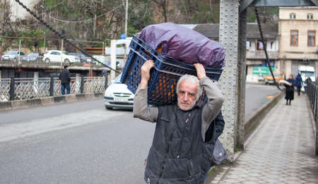 KUTAISI, GEORGIA - FEBRUARY 23, 2016: man carries goods walking on the bridge over the river Rioni.のeditorial素材