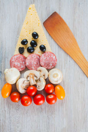 Creative composition of ingredients tomatoes, cheese, salami, mushrooms, arugula, olives in the form of a slice of pizza.の写真素材