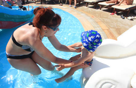 DIDIM, TURKEY - JULY 9, 2014. Mother with her baby boy swimming in the hotel pool.のeditorial素材