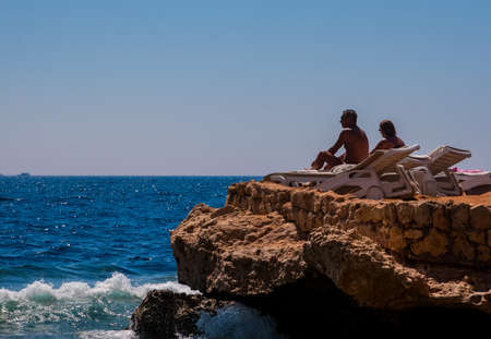 SHARM EL SHEIKH, EGYPT - JULY 9, 2009. Rear view of a romantic couple sitting on the sun loungers enjoying sea.のeditorial素材