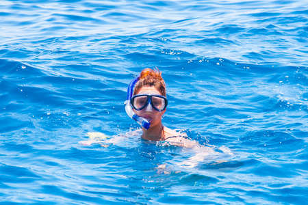 happy woman wearing a mask in the sea, along with a camera.の写真素材