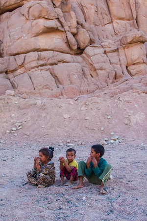 SHARM EL SHEIKH, EGYPT - JULY 9, 2009. Three children are sitting in the desert, and looking into the distance.のeditorial素材