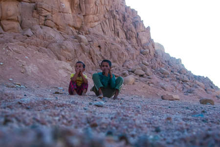 SHARM EL SHEIKH, EGYPT - JULY 9, 2009. Two children are sitting in the desert, and looking into the distance.のeditorial素材
