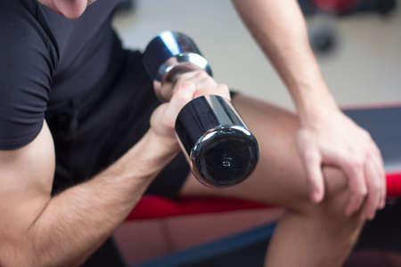 bodybuilder working out with bumbbells weights at the gym.