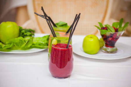 Red and green healthy smoothies with fresh ingredients on tableの写真素材