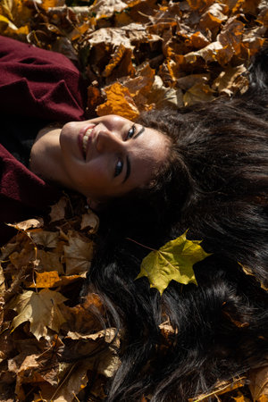 Beautiful young girl in the autumn forest on a sunny dayの写真素材