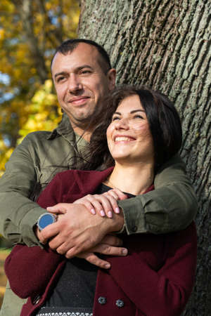 Beautiful young couple in autumn forest on a sunny dayの写真素材