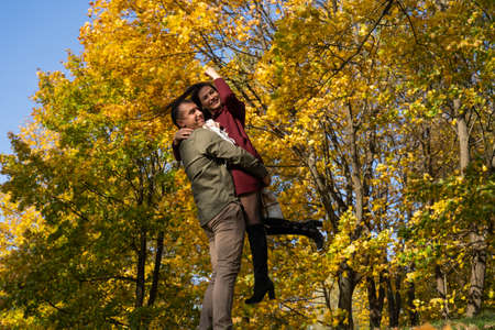 Beautiful young couple in autumn forest on a sunny dayの写真素材