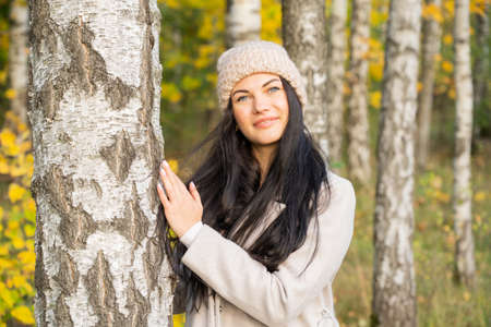 Beautiful young girl in the autumn forest on a sunny dayの写真素材