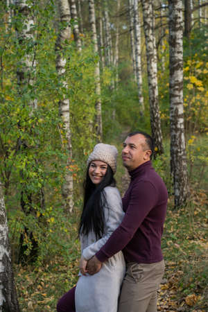 Beautiful young couple in autumn forest on a sunny dayの写真素材
