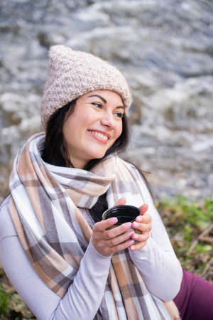 beautiful girl drinking tea near the riverの写真素材