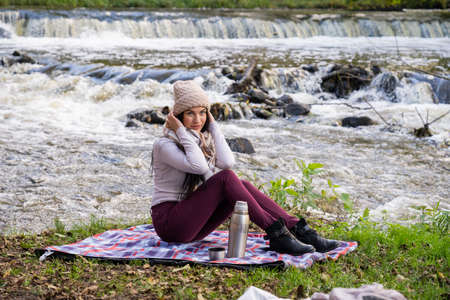 beautiful girl drinking tea near the riverの写真素材