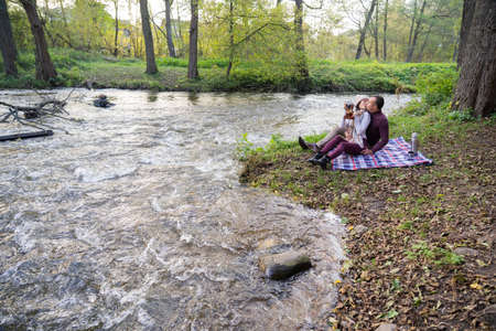a guy and a girl are drinking tea near the riverの写真素材