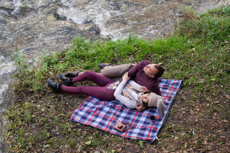 a guy and a girl are drinking tea near the riverの写真素材