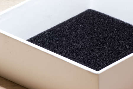 Cardboard box with cover on white table with black foam top view