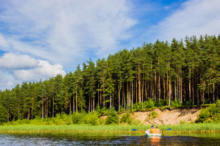 An old wooden fishing boat sailing through cane at a lakeの写真素材