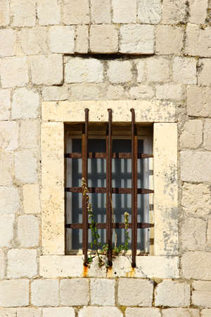 Old window with metal protection on stoned building in Dubrovnik, Croatiaの写真素材