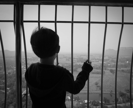 Kid Silhouette standing his hands picking and looking at fieldの写真素材