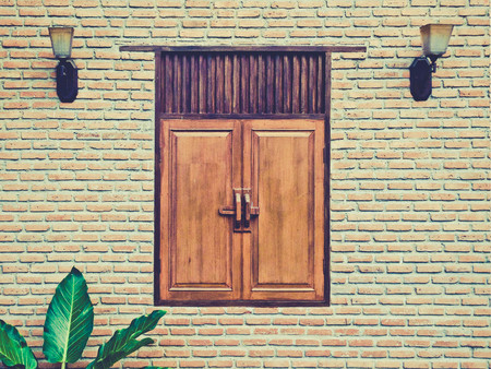 Facade of Old Building brick wall with Wooden Window Lantern and leaf vintage toneの写真素材