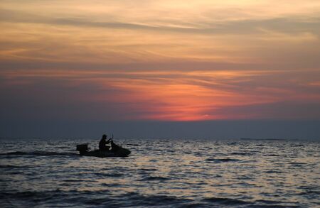 silhouette people on jetski in sunset timeの写真素材