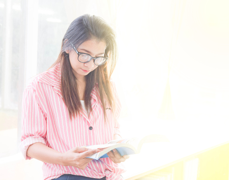 Beautiful young woman reading a book to find out information in the library. people, knowledge, education and school conceptの写真素材