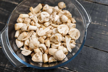 Cut forest champignons in glass bowl on black boards. Mushrooms on dark background.の写真素材