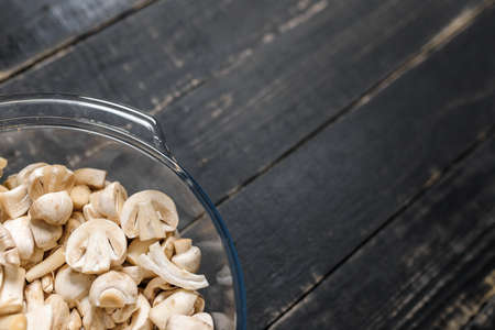 Cut forest champignons in glass bowl on black boards. Mushrooms on dark background.の写真素材