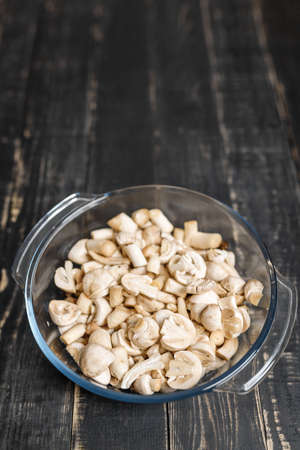 Cut forest champignons in glass bowl on black boards. Mushrooms on dark background.の写真素材