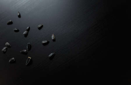 Sunflower seeds thrown around on black wooden table.  Healthy, organic, vegetarian food concept.  Tasty snack. Top view. Place for text.の写真素材