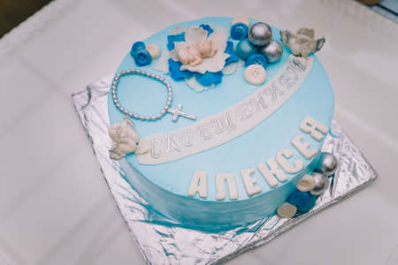 Blue cake with mastic cross and angels for boy christening party. Inscription - Baptism of Alexey.