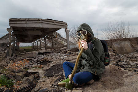Human in gas mask among ruins and dramatic sky background. Enviromental pollution, ecology disaster,...