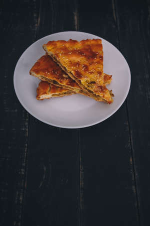 Some pieces of meat and carrot pie on white plate on black wooden background. Tasty healthy food. Diet, nutrition, eating habits concept. Vertical shot, place for text.の写真素材