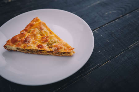 Piece of meat and carrot pie on white plate on black wooden background. Tasty healthy food. Diet,...