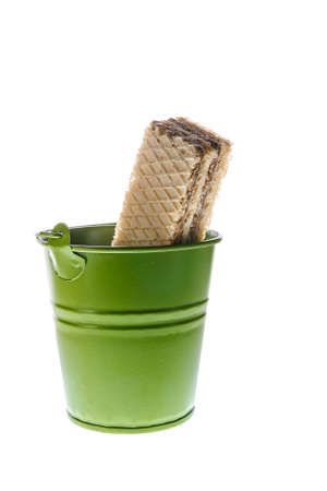 Sweet rectangular shaped waffles with multilayer and chocolate or cacao filling in green bucket isolated on white background. Fat unhealthy  fast food, diet, nutrition, overweight, junk food concept.の写真素材