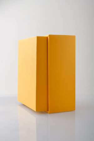 Yellow orange closed cardboard box or carton on gray background, template, mockup, sideview.