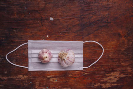 Two garlic bulbs on gauze mask. Influenza, covid 19, inflammation prevention. Natural antioxidant...