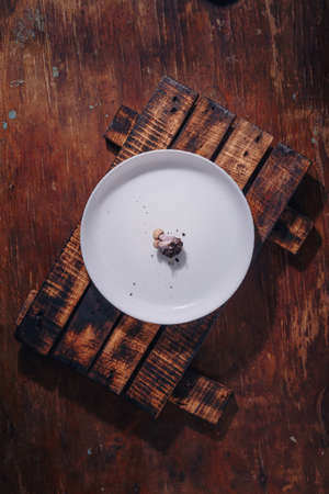 Two tiny tricholoma mushrooms with soil on white plate. Undereating, underweight, anorexia, diet restrictions, eating problems, disorder. Top view, close up shotの写真素材