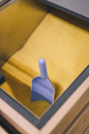 Soft focused vertical shot of blue plastic scoop in some yellow groats. Grocery department, pet food shop. Copy spaceの写真素材