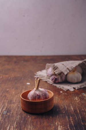 Garlic in pot, wooden kitchen background. Anti-fungal, anti-cancer, anti-inflammatory vegetable, herbal medicine. Copy space, vertical shotの写真素材